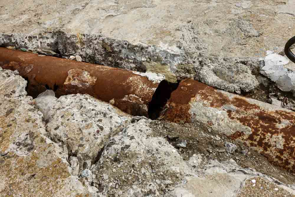 Fragments of old cast-iron water pipes. After many years of operation corroded metal pipe was destroyed. Rusty steel tube with holes of metallic corrosion. Rusty cast iron, metal