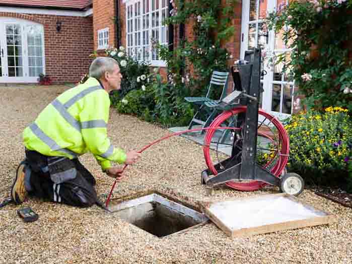 BUCKINGHAM, UK - October 16, 2019. A professional drain cleaning engineer inspects a blocked household drain